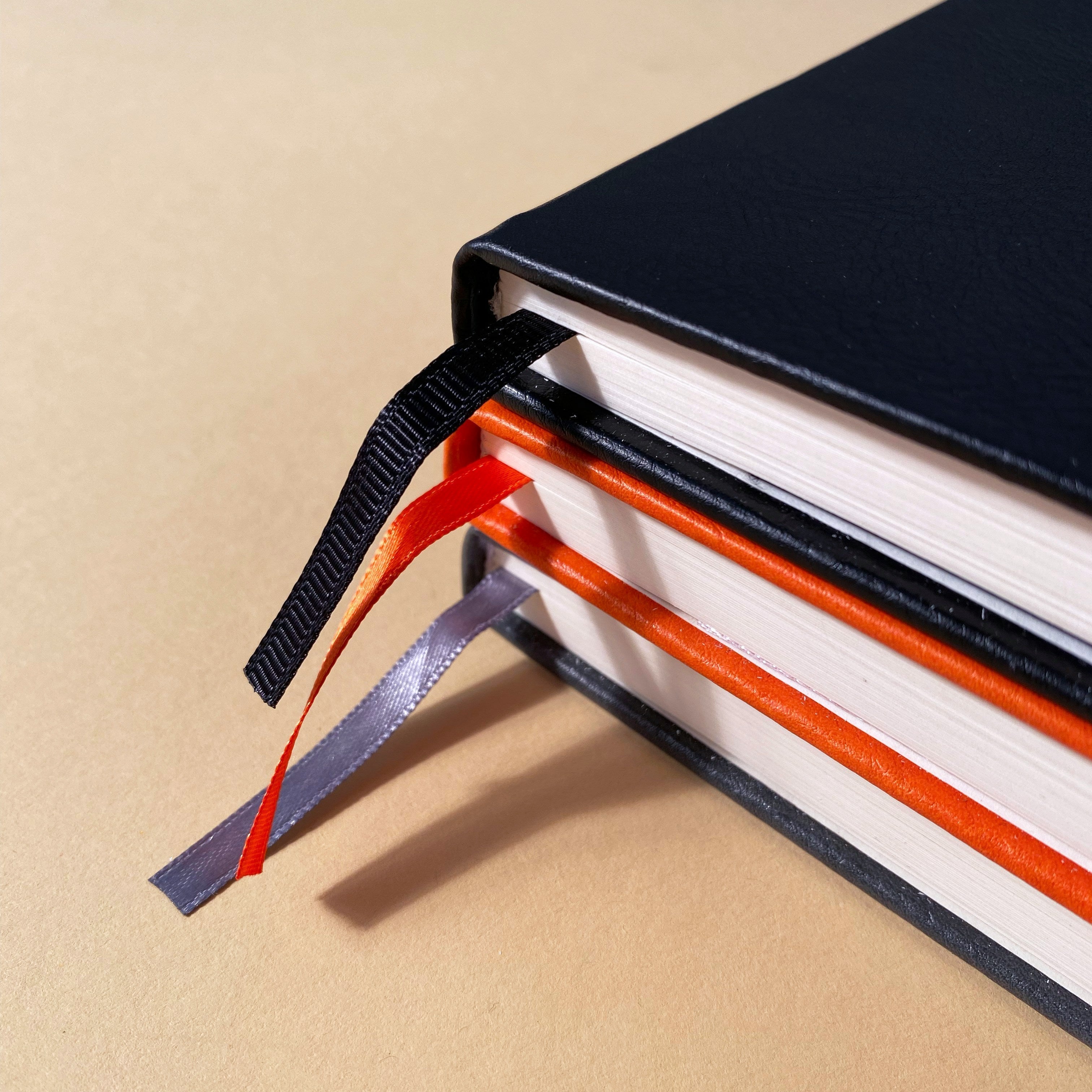 Stack of three colorful notebooks with bookmarks representing organized stationery