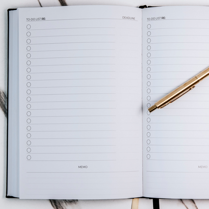 The Productivity Notebook on a desk, open to the to-do list layout with a gold pen